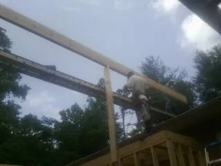 Carpenter setting a ridge beam over a new addition frame — Ice Dam Removal by Roofing Brothers in Riverdale